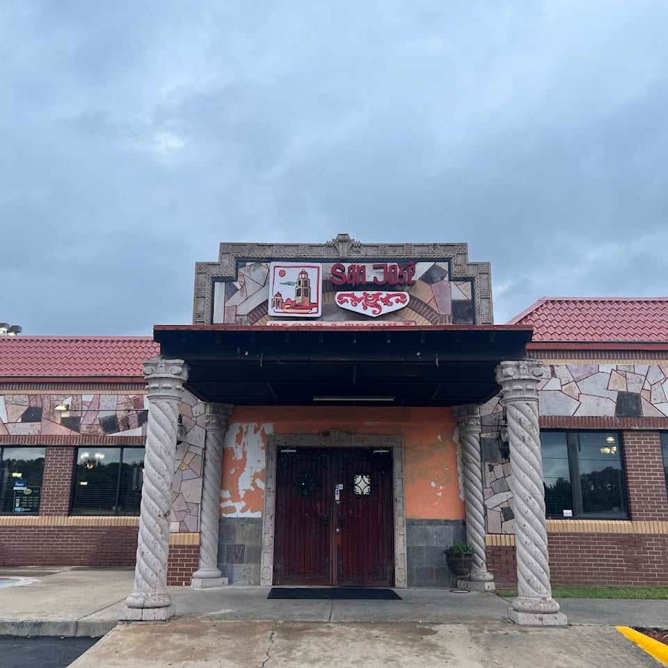 Exterior of San Jose Mexican Restaurant with a stone facade, red tile roof, and ornate columns.